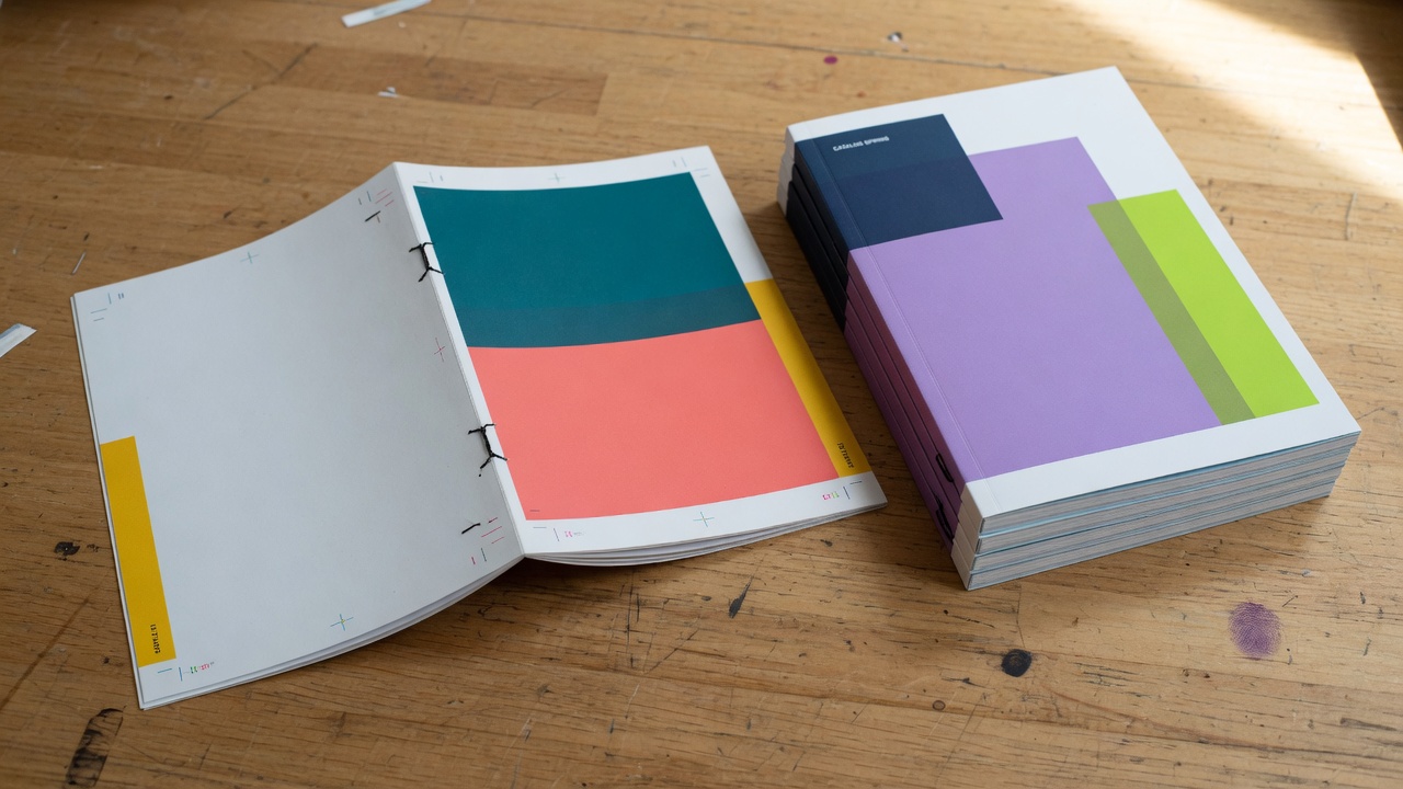 Saddle-stitched booklet next to a perfect-bound catalog